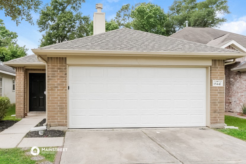 a white garage door in front of a brick house