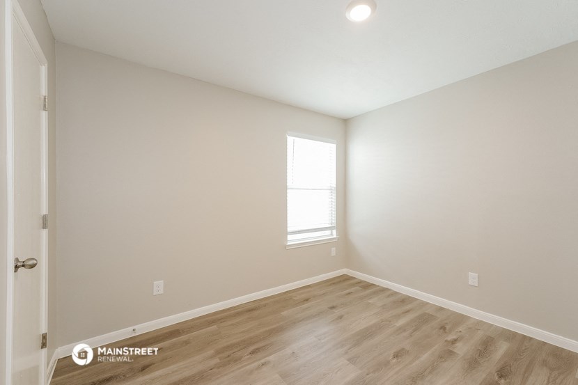 the spacious living room with wood flooring and a window