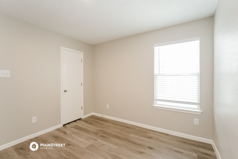 the upstairs bedroom with wood flooring and a window