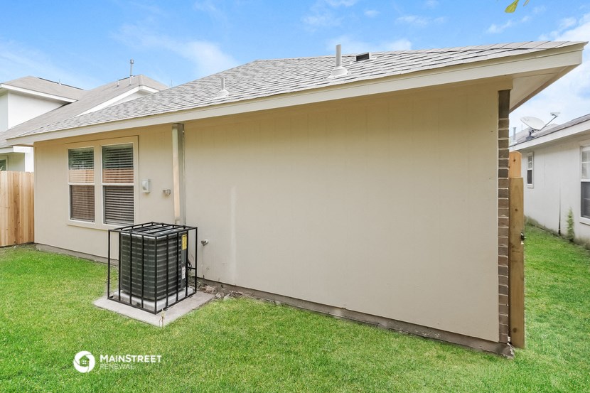 the backyard of a house with a patio and a trash can