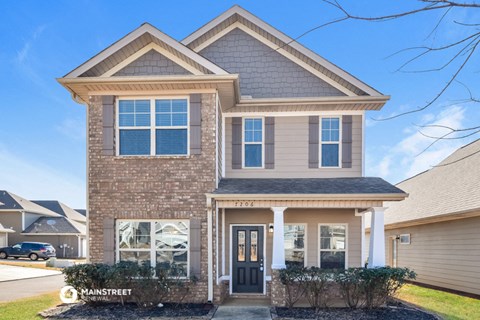 a tan brick house with a black front door