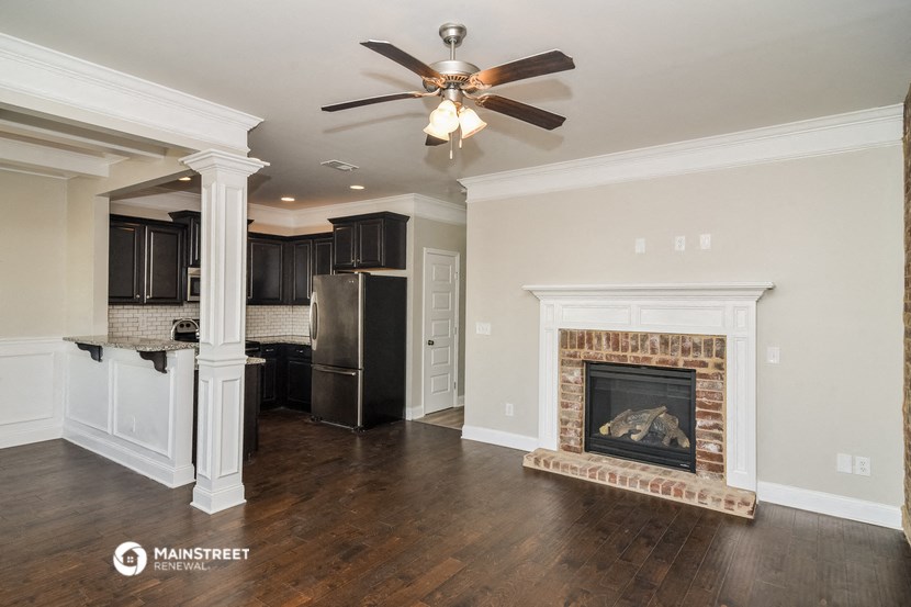 a living room with a fireplace and a kitchen with black cabinets