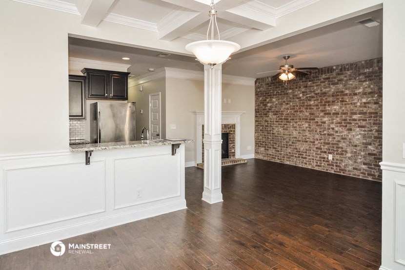 the living room and kitchen of a house with a brick wall