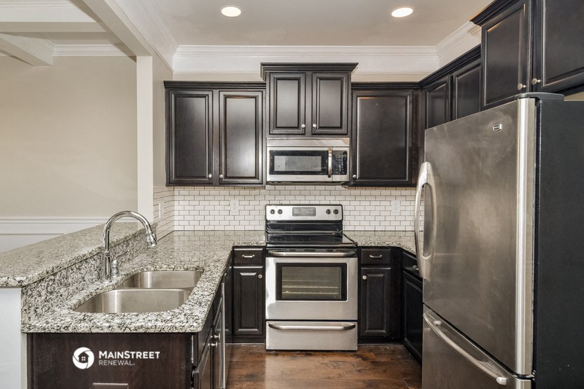a kitchen with black cabinets and granite counter tops and stainless steel appliances
