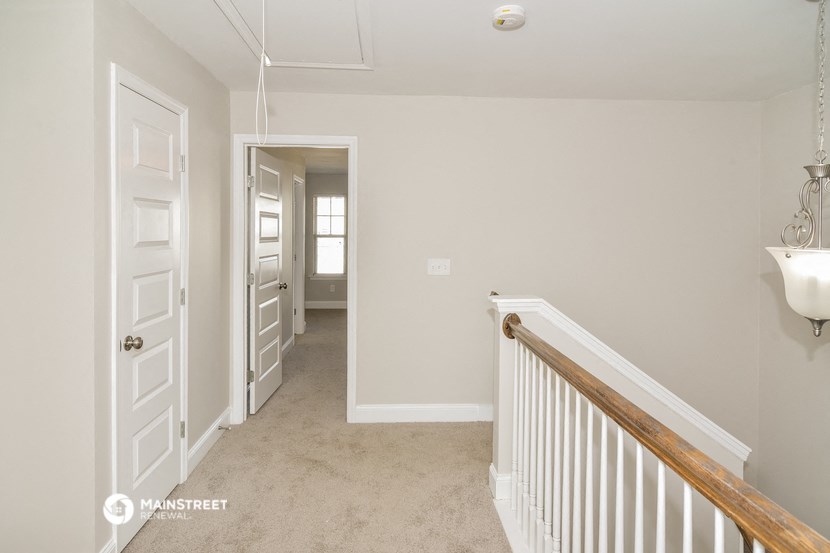 a hallway of a home with a staircase and a door to a hallway with a