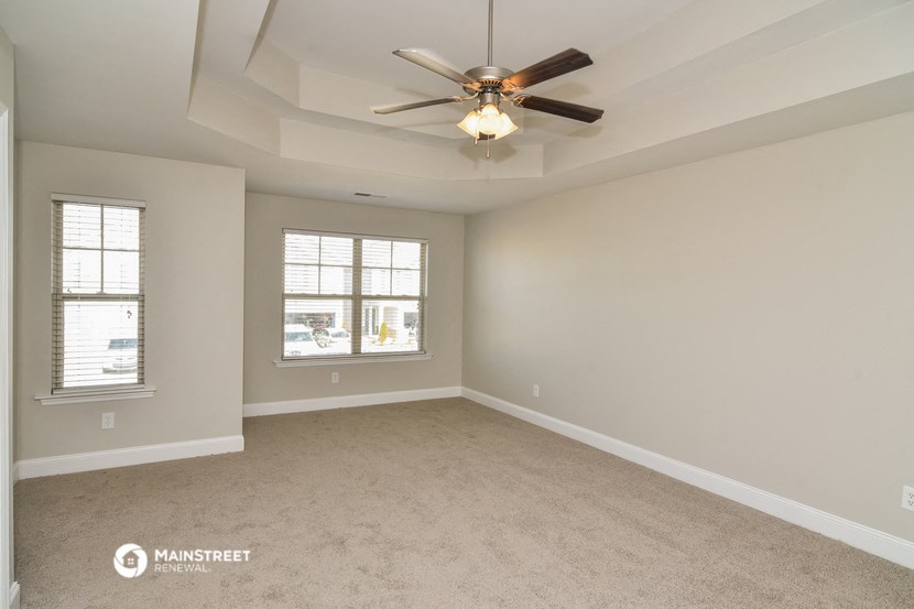 the spacious living room with ceiling fan and windows