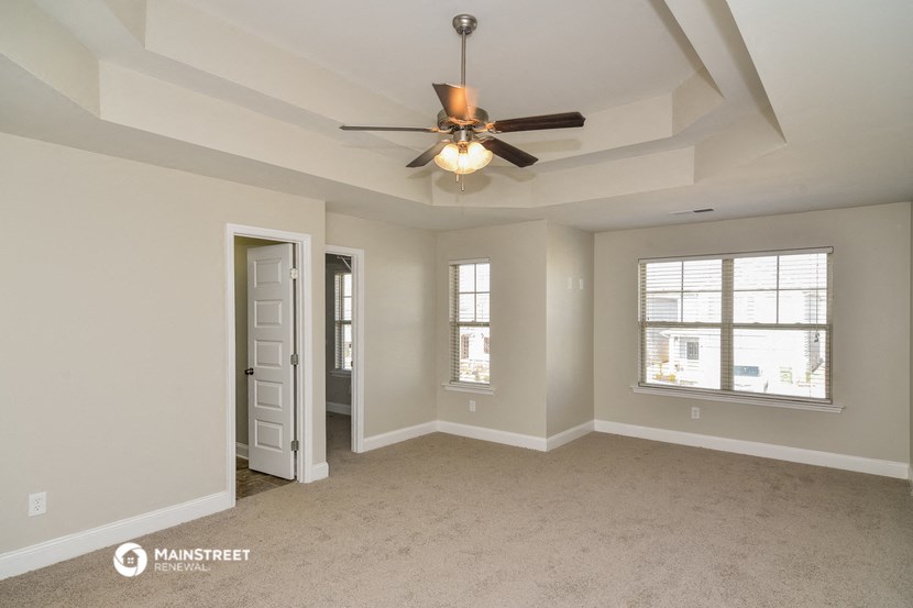 the living room of an empty home with a ceiling fan