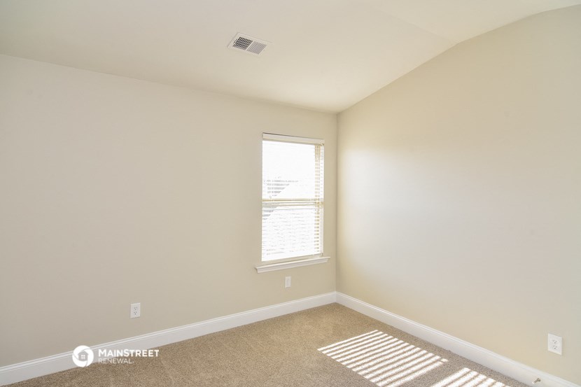 a bedroom with white walls and a window