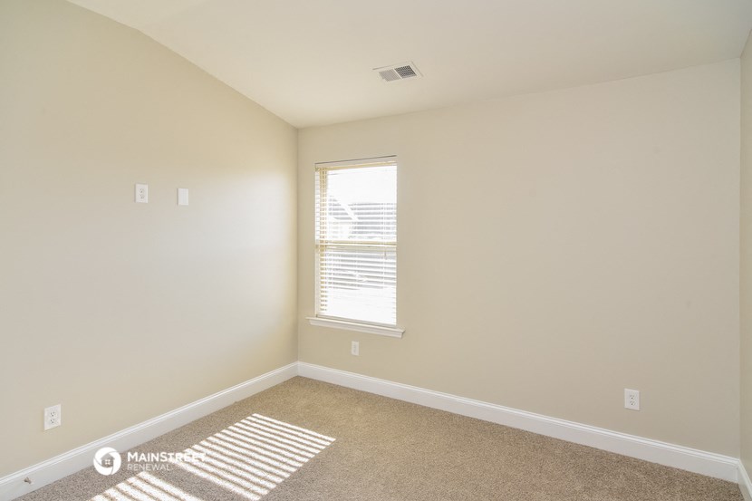 a bedroom with white walls and carpet and a window