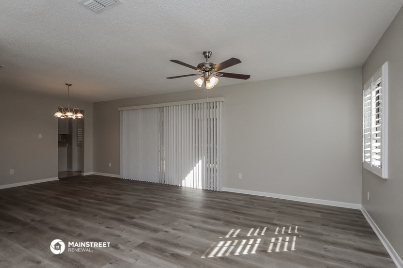 an empty living room with a ceiling fan and window
