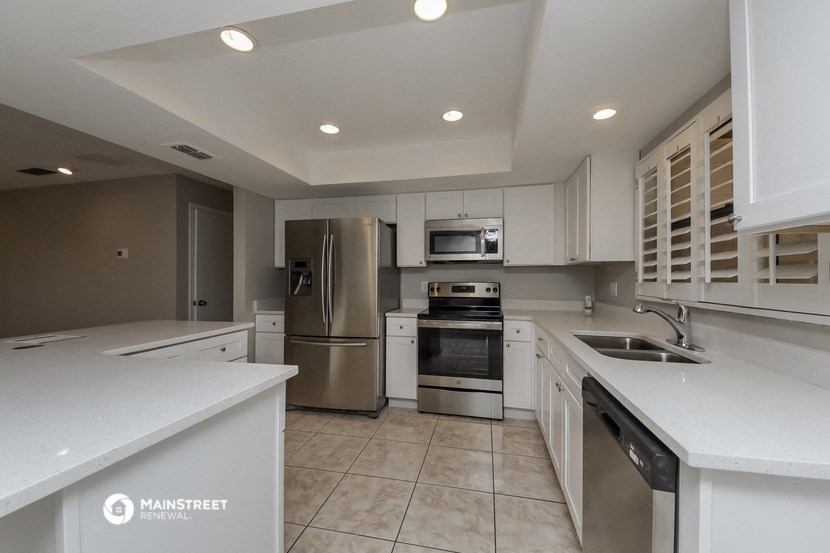 a white kitchen with stainless steel appliances and white counters