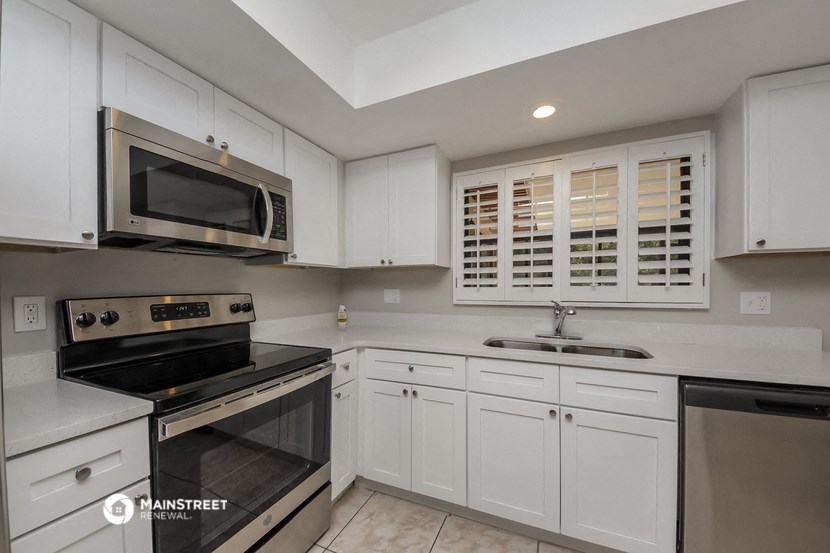 a kitchen with white cabinets and black appliances