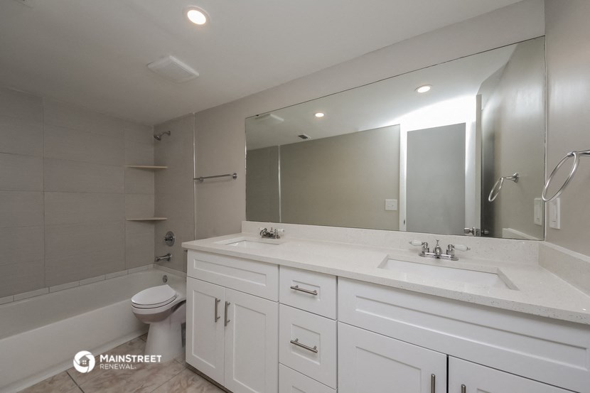 a white bathroom with a large mirror and a toilet and sink