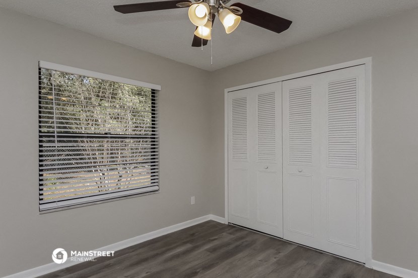 the living room of a home with a large window and a ceiling fan