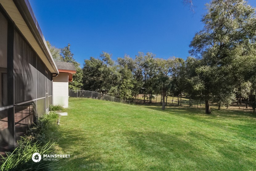 a backyard with trees and a fence and a house
