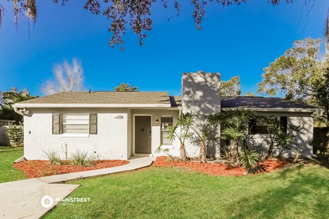 a white house with a lawn and palm trees