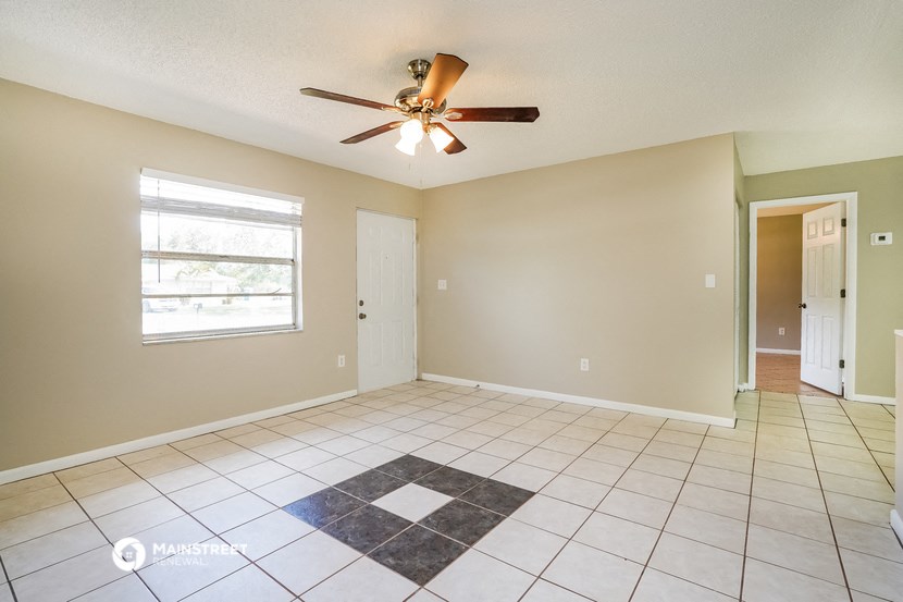 an empty living room with a ceiling fan and tiled floor