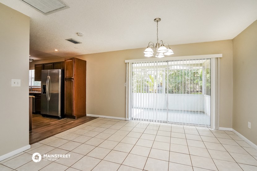 an empty living room with a sliding glass door to a kitchen