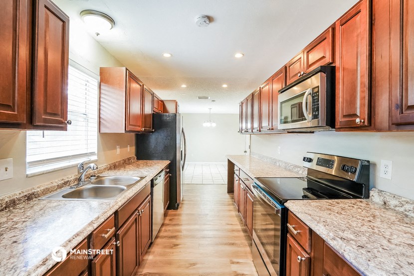 a kitchen with wooden cabinets and granite counter tops and a black stove and microwave