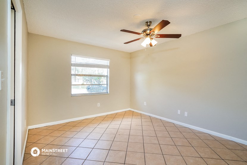 an empty living room with a ceiling fan and tiled floors