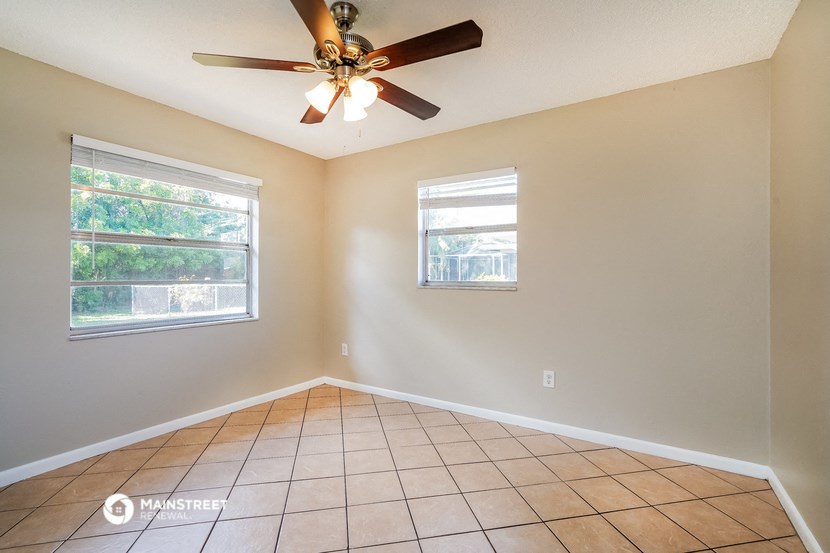an empty living room with a ceiling fan and tiled floors