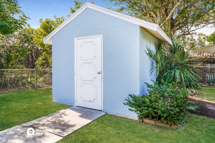 a small blue shed with a white door in a backyard