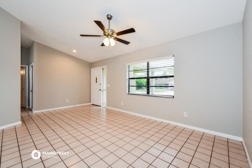 an empty living room with a ceiling fan and a window