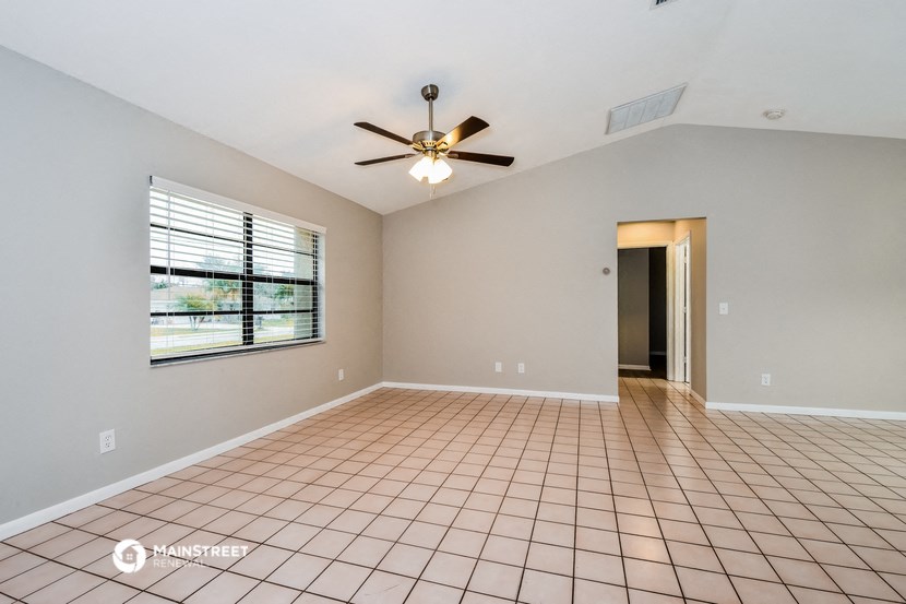 an empty living room with a ceiling fan and a window