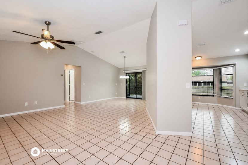 the spacious living room with tile flooring and a ceiling fan