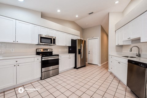 a large kitchen with white cabinets and black appliances