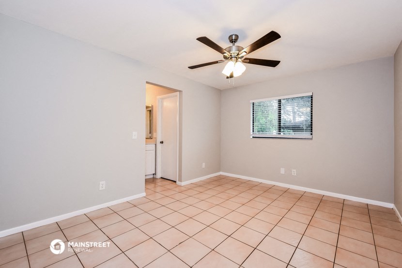 the living room has a ceiling fan and tile flooring