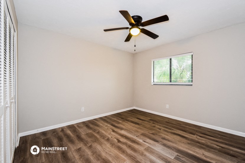 the great room with hardwood floors and a ceiling fan