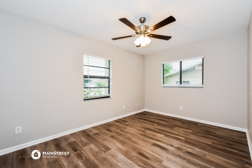 the spacious living room with hardwood floors and a ceiling fan
