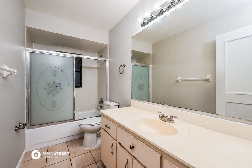 a bathroom with a large mirror and a sink and a toilet
