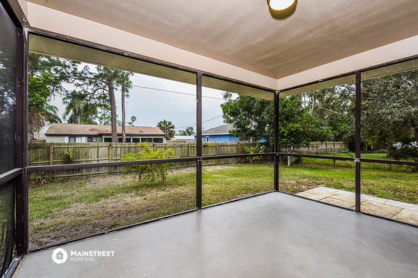 a screened in porch with glass doors and a yard