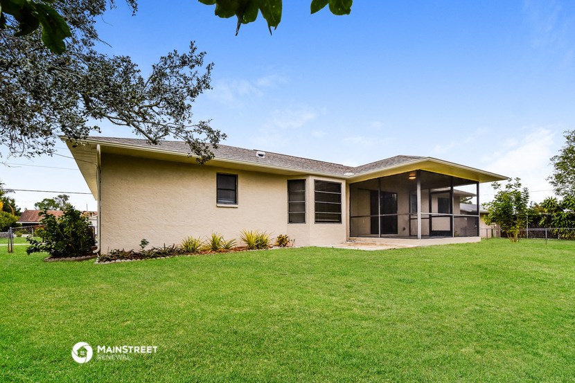 a white house with a green lawn and a tree