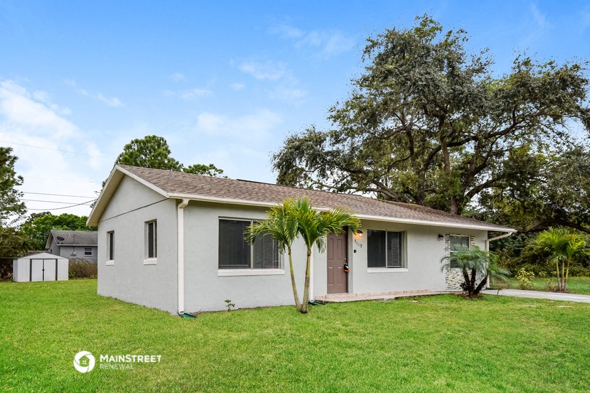 a small white house with a palm tree in the yard
