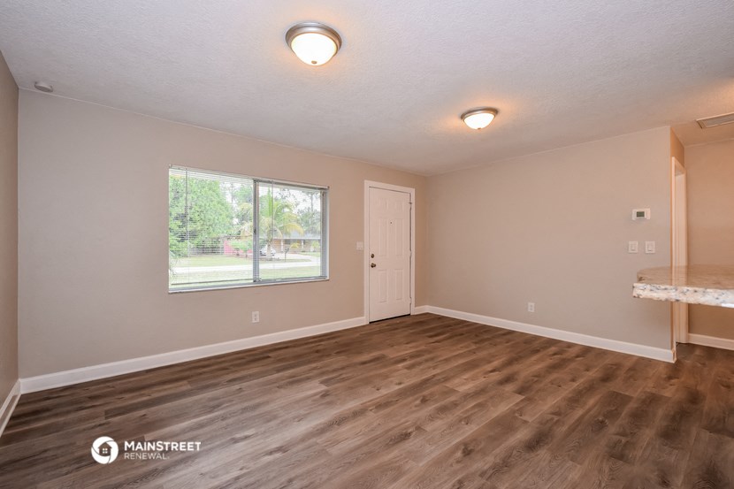 the spacious living room with wood flooring and a large window