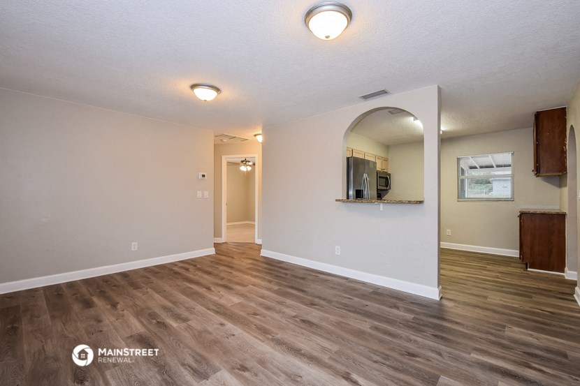 the spacious living room with hardwood flooring and white walls