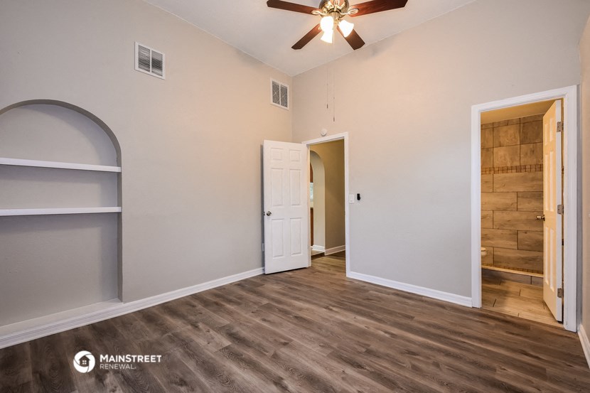 the living room of a house with a door and a ceiling fan