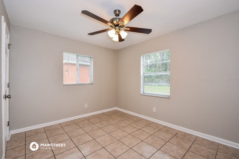 the spacious living room has a ceiling fan and tile flooring
