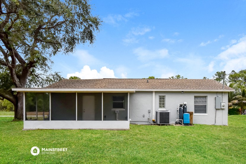 a small white house with a lawn and a tree