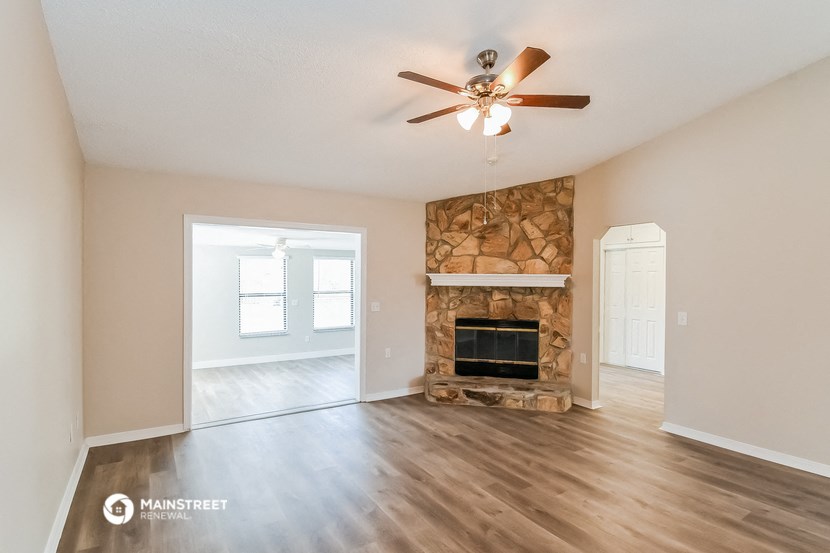 an empty living room with a fireplace and a ceiling fan