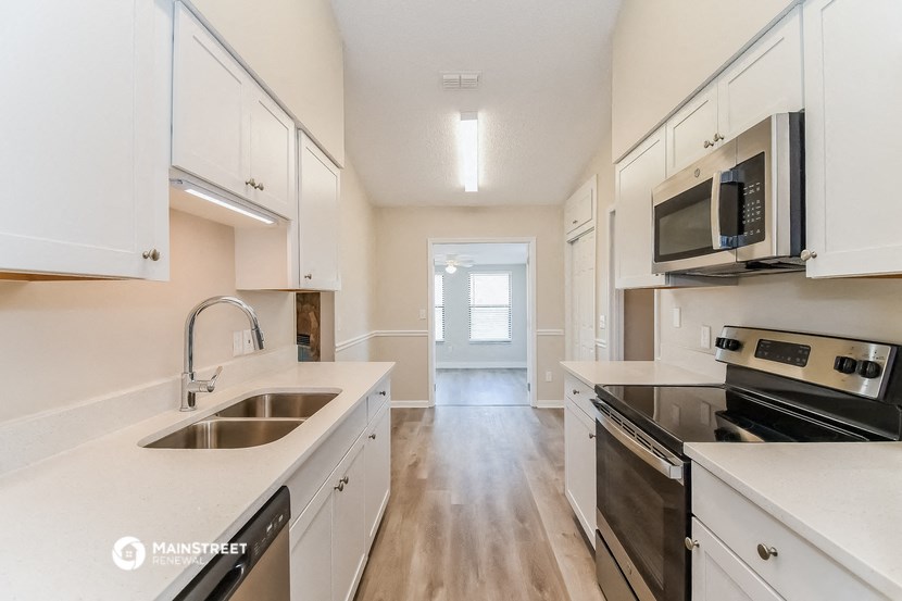 an empty kitchen with white cabinets and stainless steel appliances