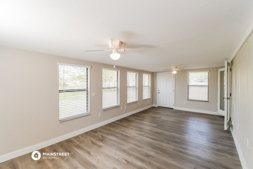 an empty living room with a ceiling fan and windows