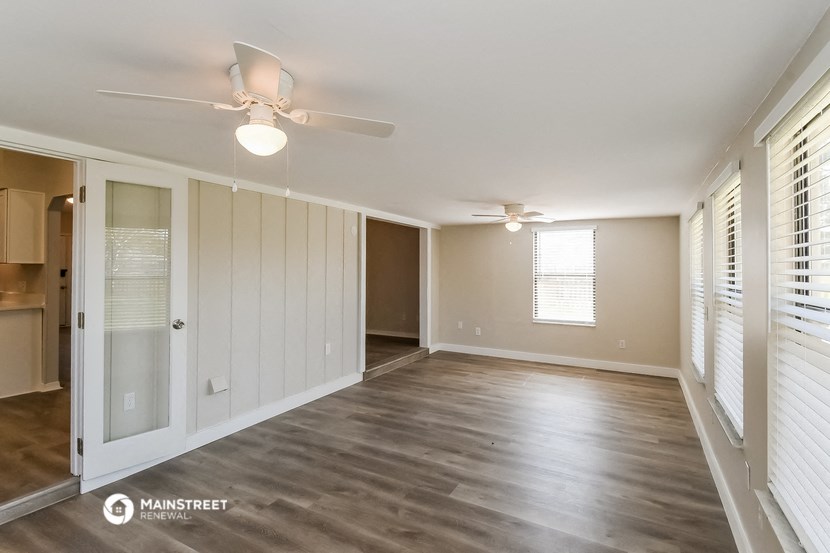an empty living room with a ceiling fan and window
