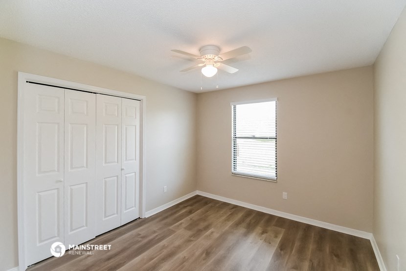 the spacious living room with a ceiling fan and wood flooring