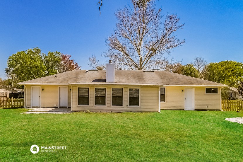 a cream colored house with a grassy yard and a tree