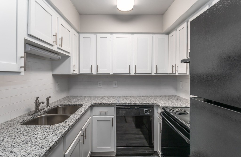 a kitchen with granite counter tops and white cabinets