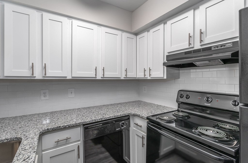 a kitchen with granite counter tops and white cabinets